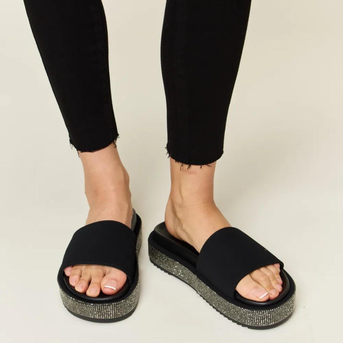 Lifestyle view of the Forever Link rhinestone sandals, perfect for a summer night out.