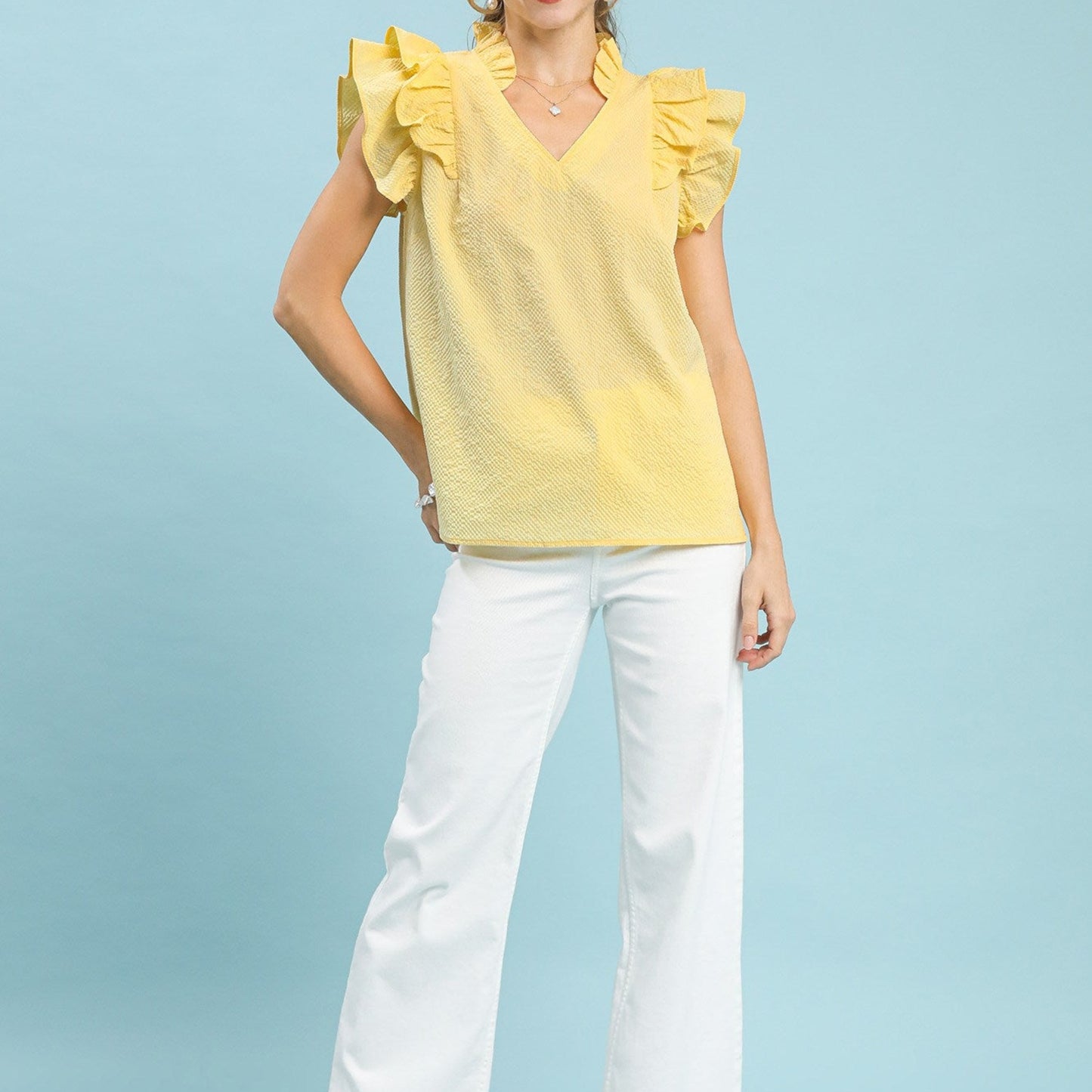 Lifestyle shot of the ice lemon textured blouse paired with white pants.
