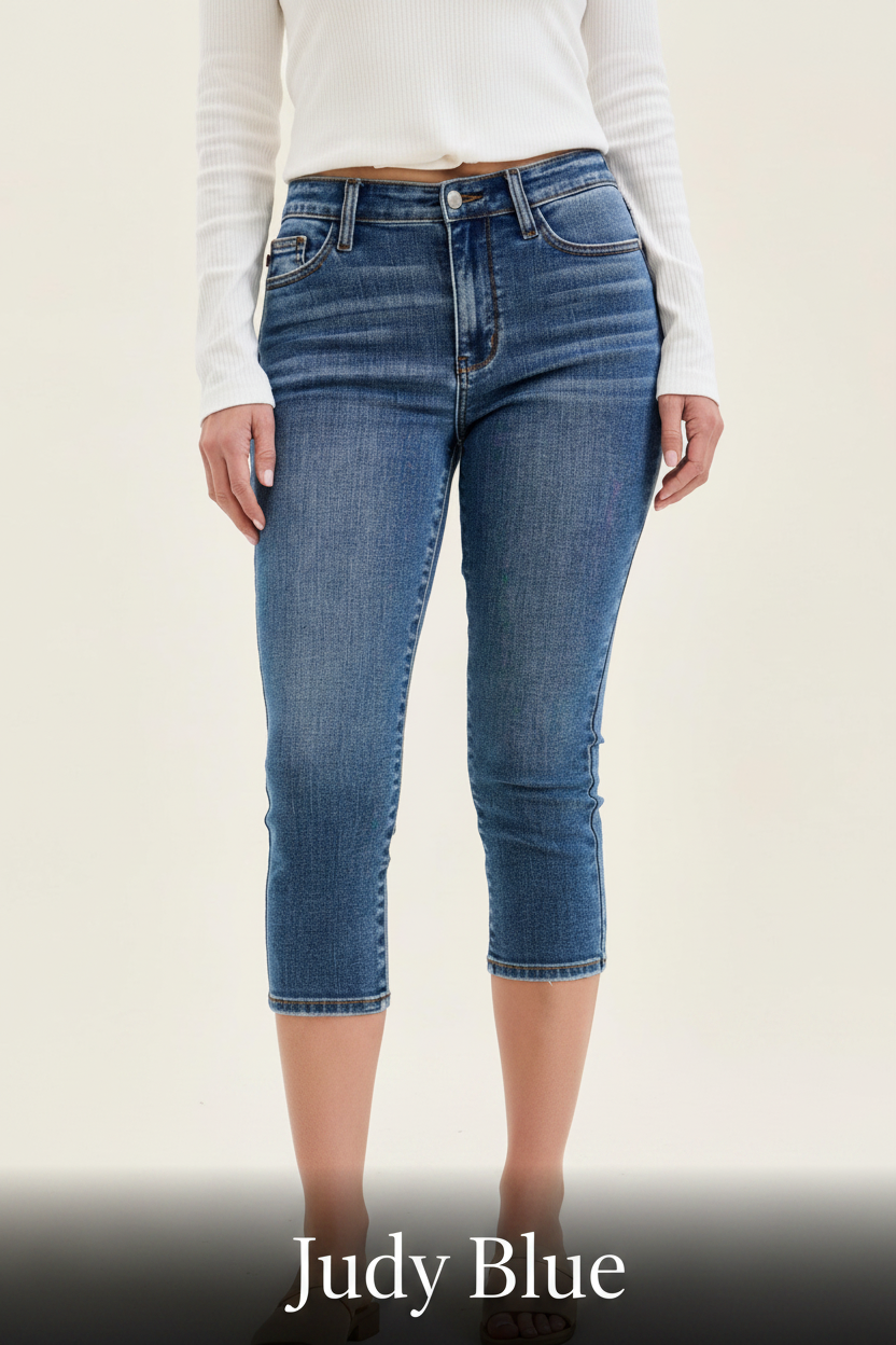 A lifestyle shot featuring a model in high-waisted Judy Blue flare jeans and a tucked-in tank top in a bright, airy setting.