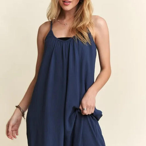 Woman wearing a blue sleeveless dress against a beige background