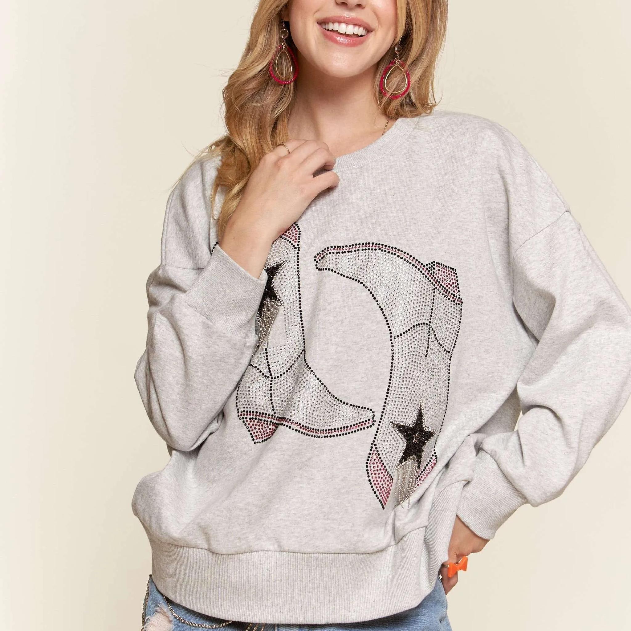 Woman wearing a gray sweatshirt with a star and moon design on a beige background