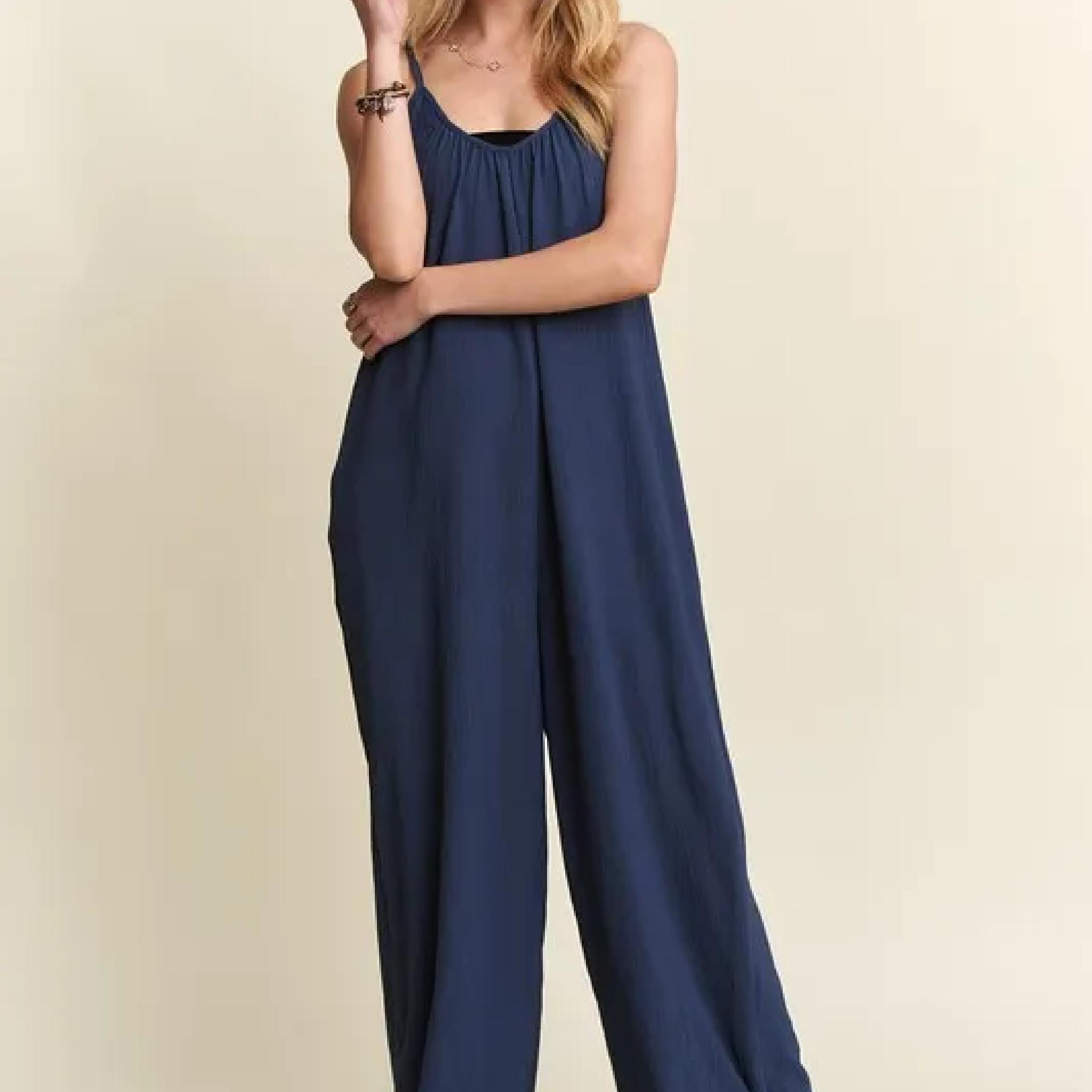 Navy blue jumpsuit worn by a person on a beige background