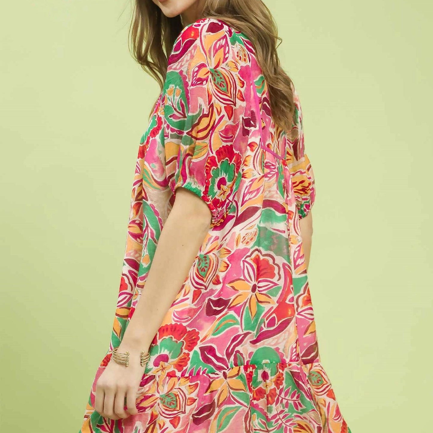 Woman wearing a colorful floral dress against a light green background