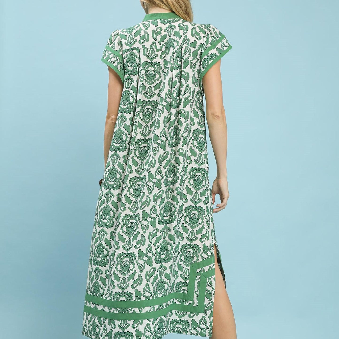 Woman wearing a green and white patterned dress against a light blue background