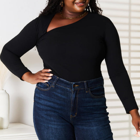 Woman wearing a black long-sleeve top and blue jeans indoors.
