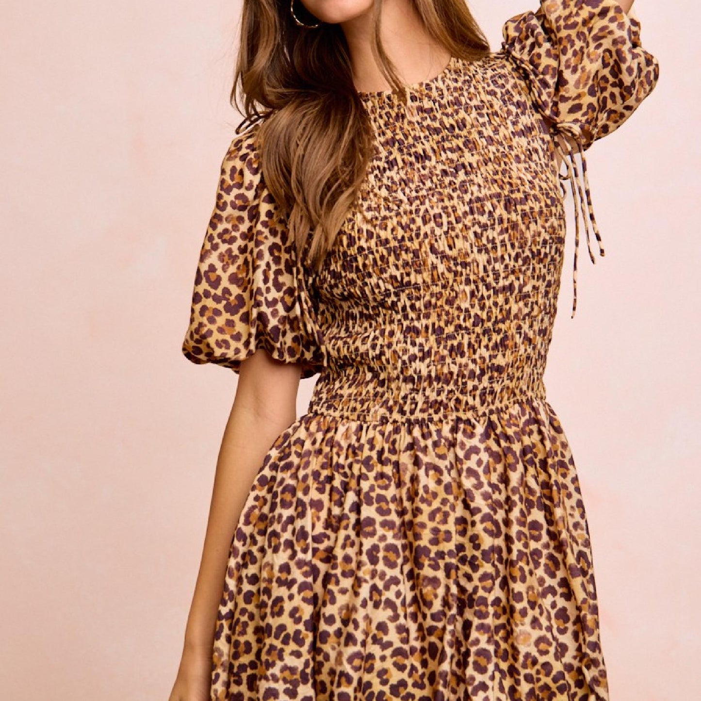 Woman wearing a leopard print dress against a pink background