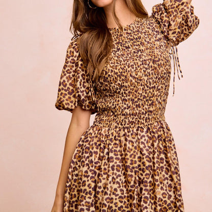 Woman wearing a leopard print dress against a pink background