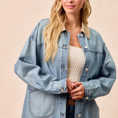 Woman wearing a light blue denim jacket on a beige background