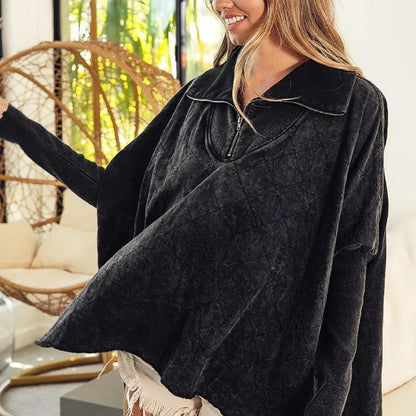 Woman wearing a dark gray poncho in a living room setting