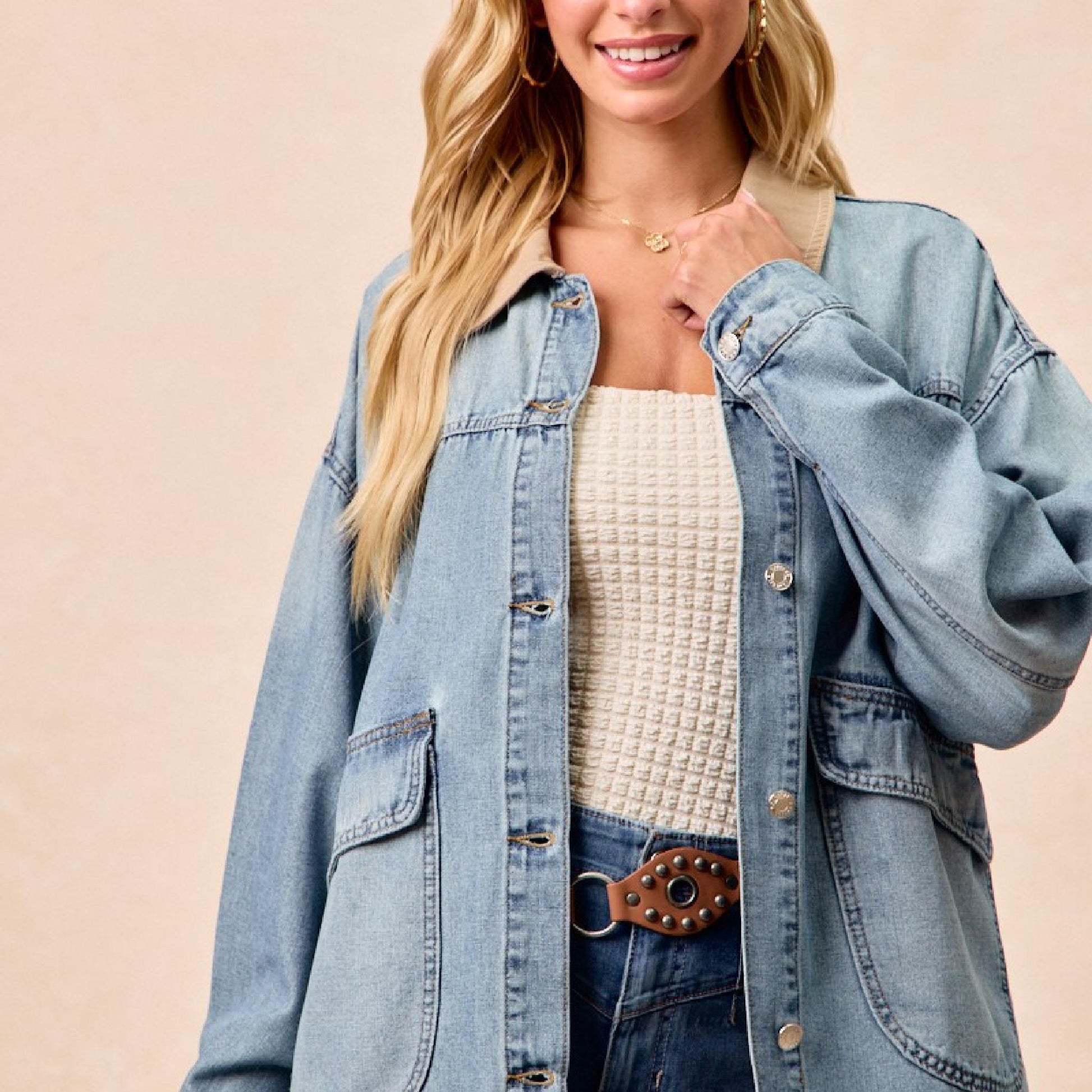 Woman wearing a denim jacket over a white top on a beige background