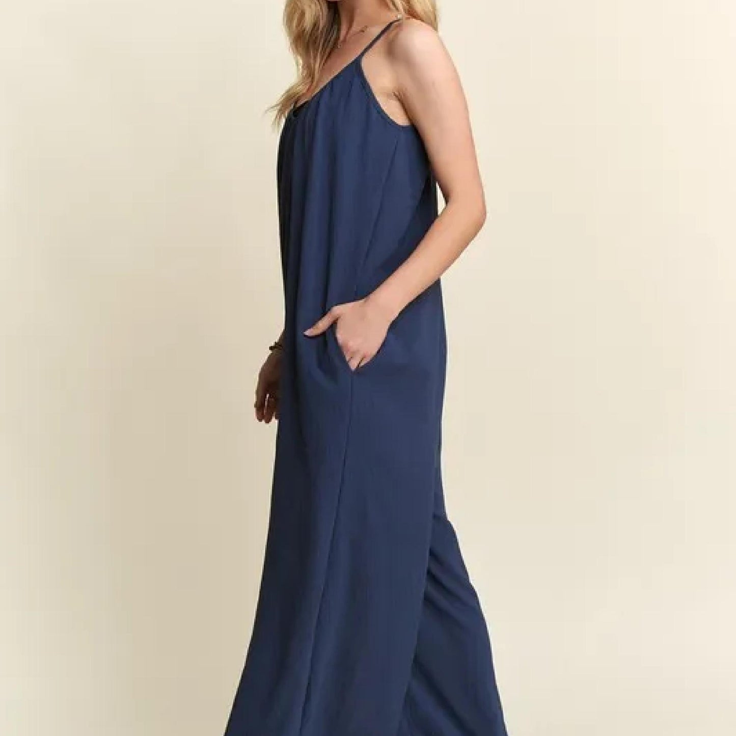 Woman wearing a long navy dress against a beige background
