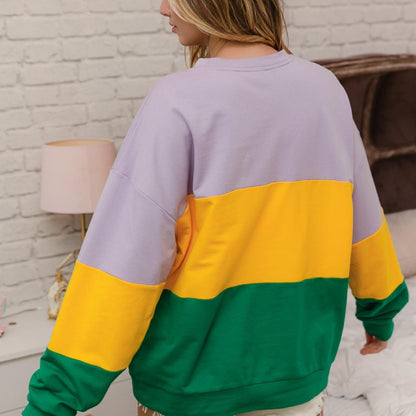 Person wearing a colorful sweatshirt with a brick wall background