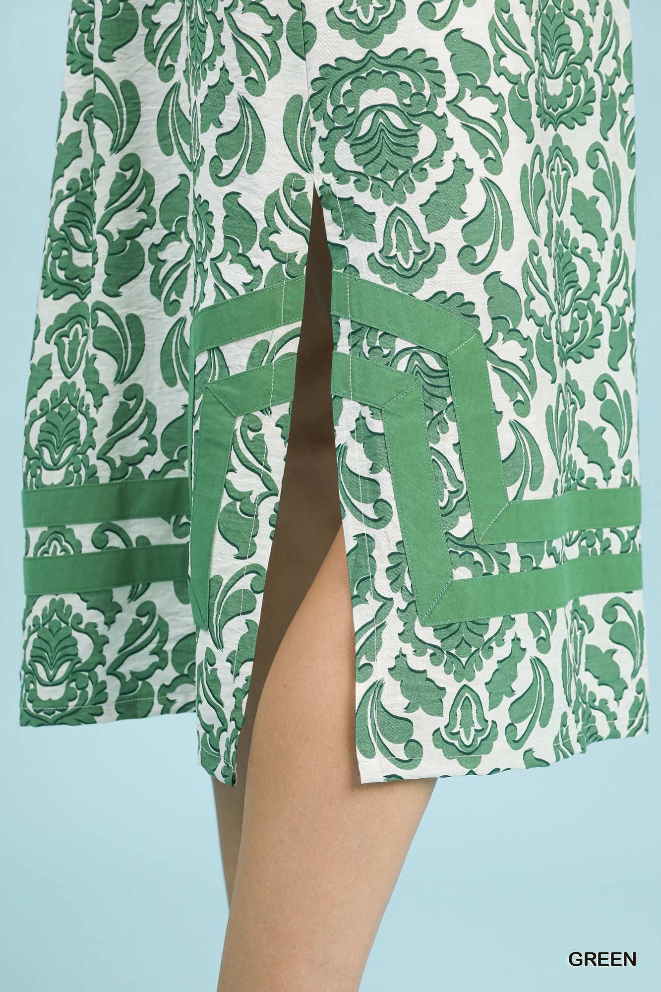 Green and white patterned dress with a slit on a light blue background