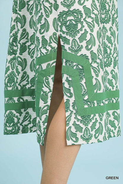 Green and white patterned dress with a slit on a light blue background