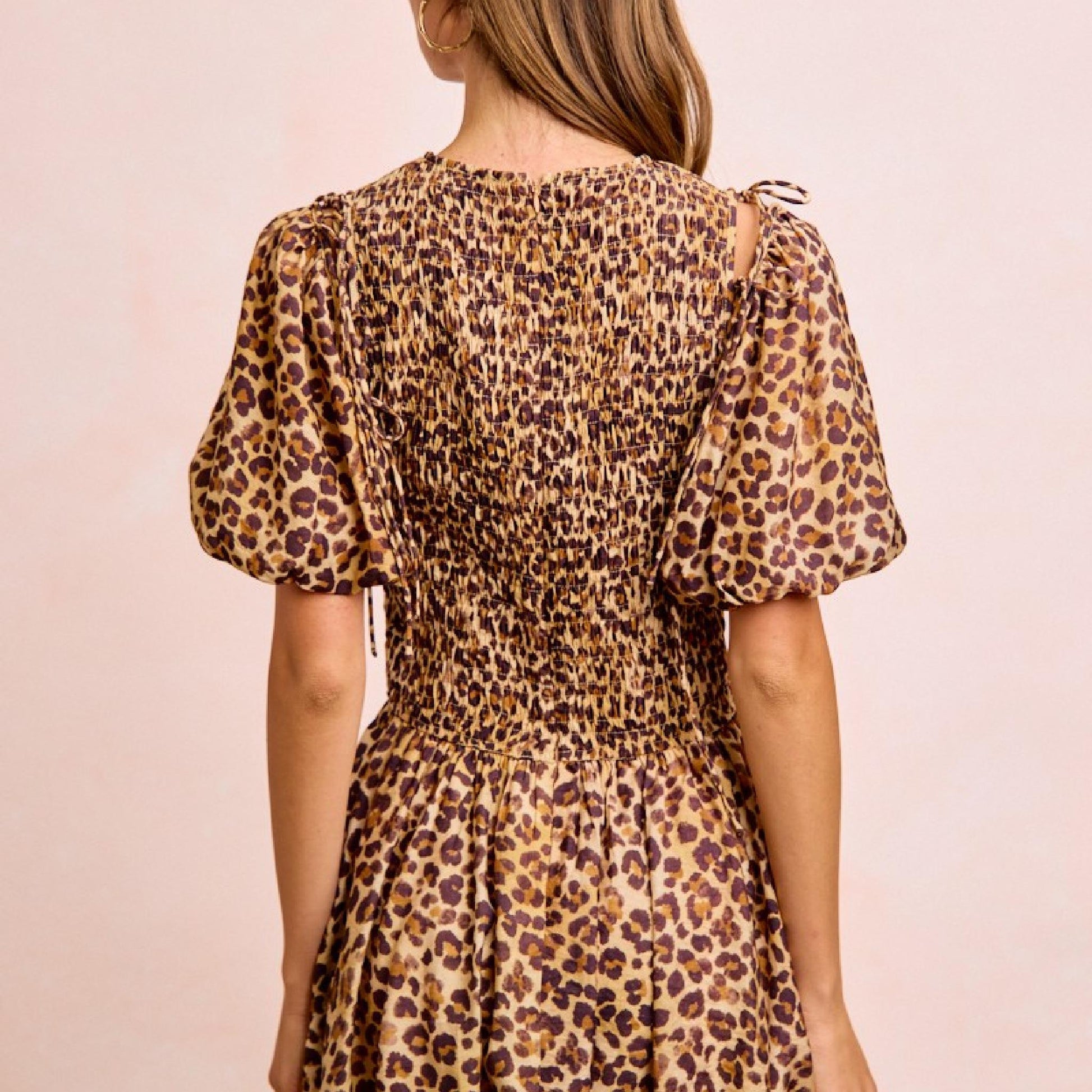 Woman wearing a leopard print dress against a beige background