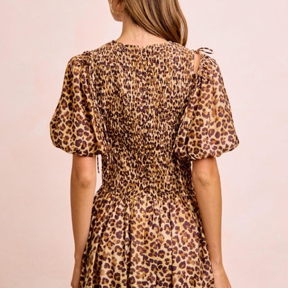 Woman wearing a leopard print dress against a beige background