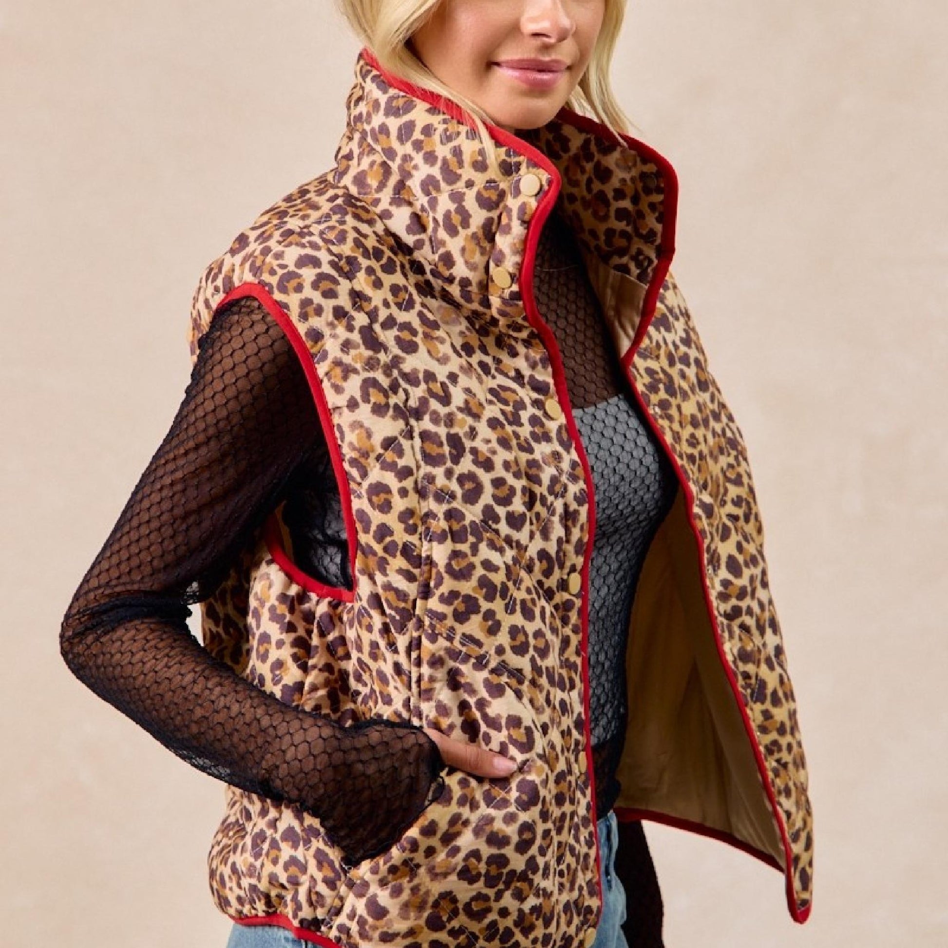 Leopard print vest with red trim worn by a person on a beige background