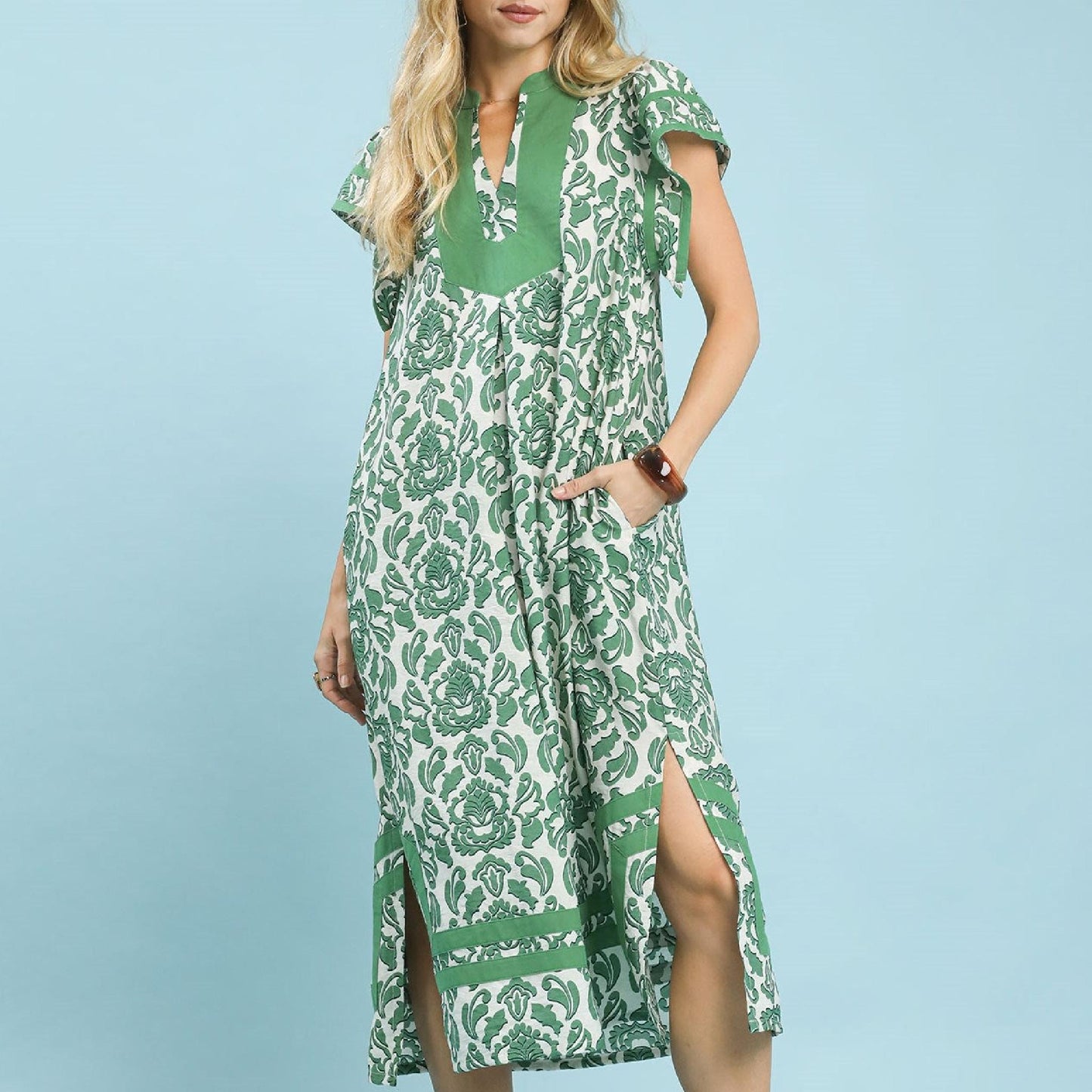Woman wearing a green and white patterned dress against a light blue background