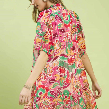Woman wearing a colorful floral dress against a light green background