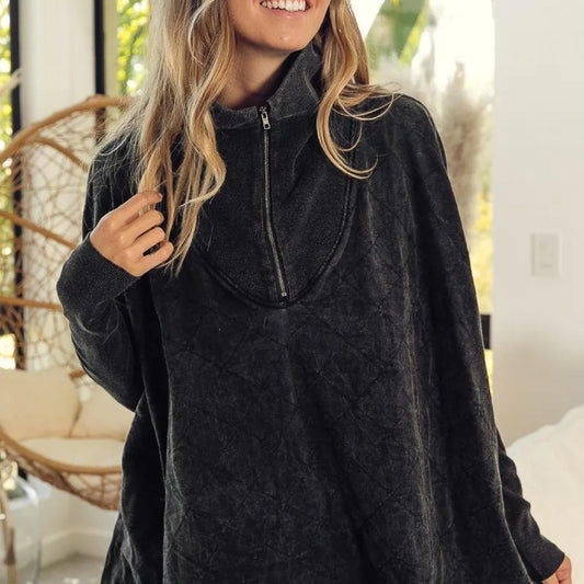 Woman wearing a dark gray poncho in an indoor setting