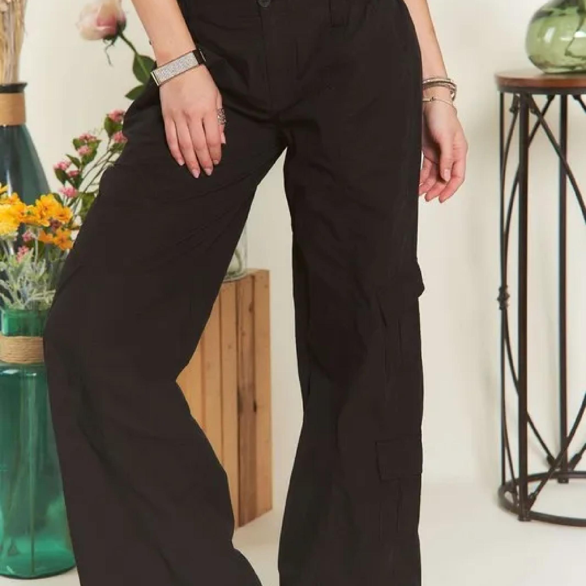 Person wearing black cargo pants in a room with decorative elements.