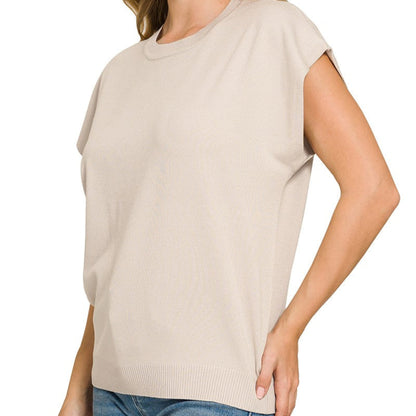 Woman wearing a beige sleeveless top and blue jeans on a white background