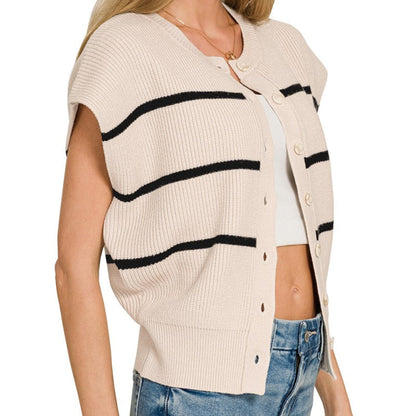Woman wearing a sand beige cardigan with black stripes and blue jeans on a white background