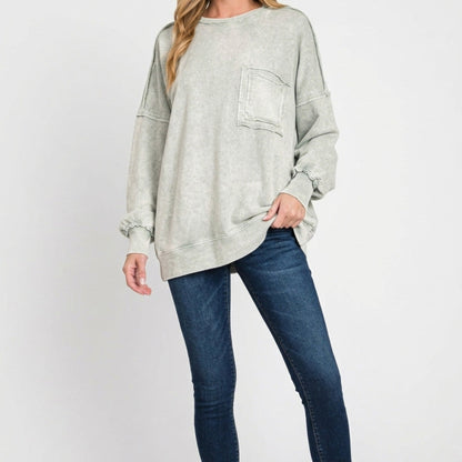 Woman wearing a light gray oversized sweater and blue jeans on a white background