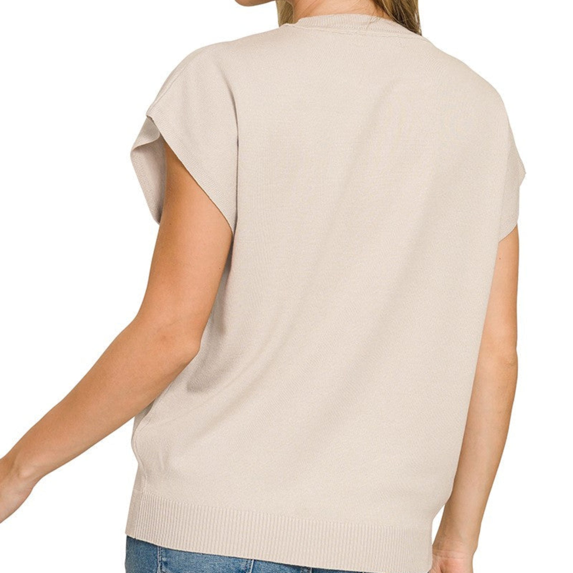 Woman wearing a beige short-sleeve top and blue jeans on a white background