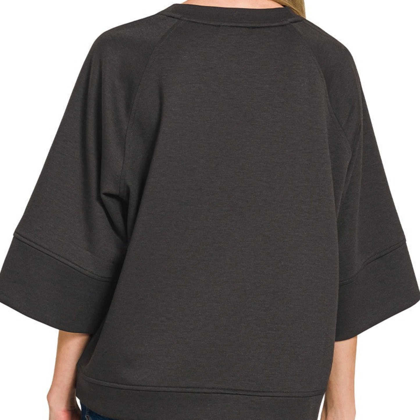 Person wearing a black oversized sweater with a plain background