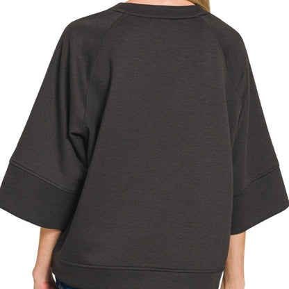 Person wearing a black oversized sweater with a plain background