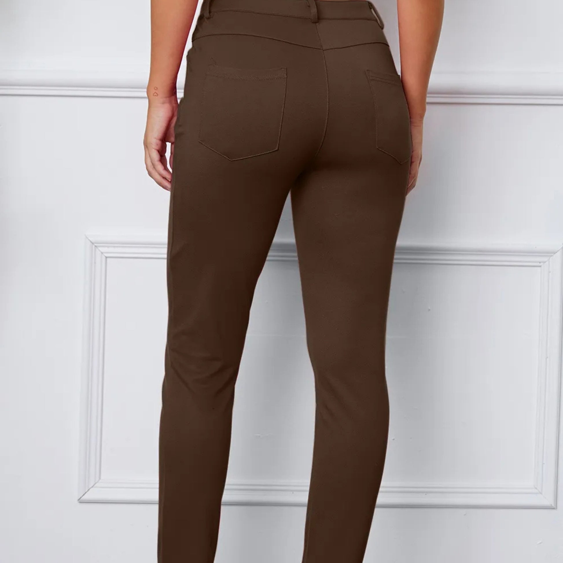 Brown pants worn by a person against a white paneled wall