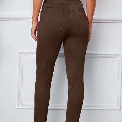 Brown pants worn by a person against a white paneled wall
