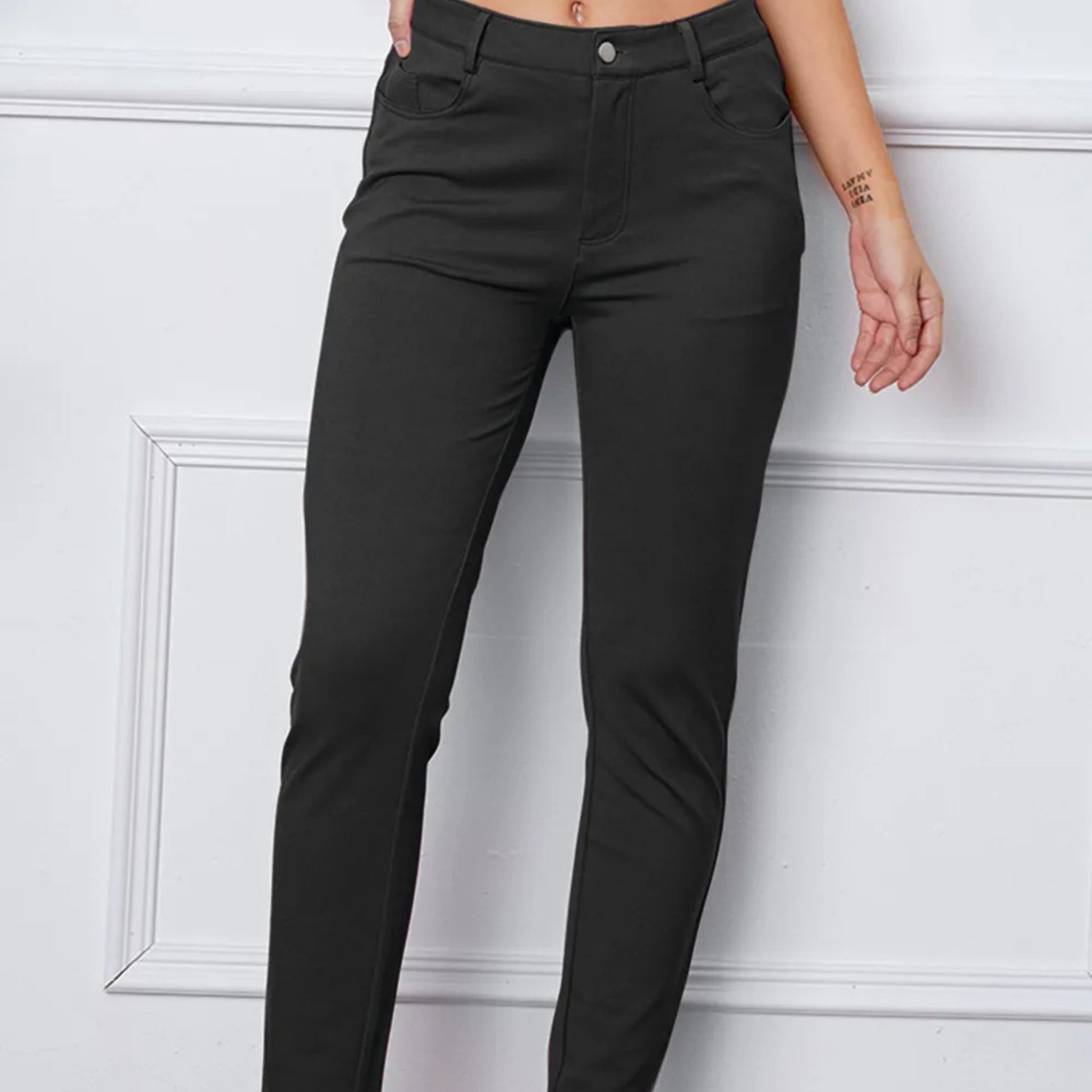 Dark grey pants worn by a person against a white wall