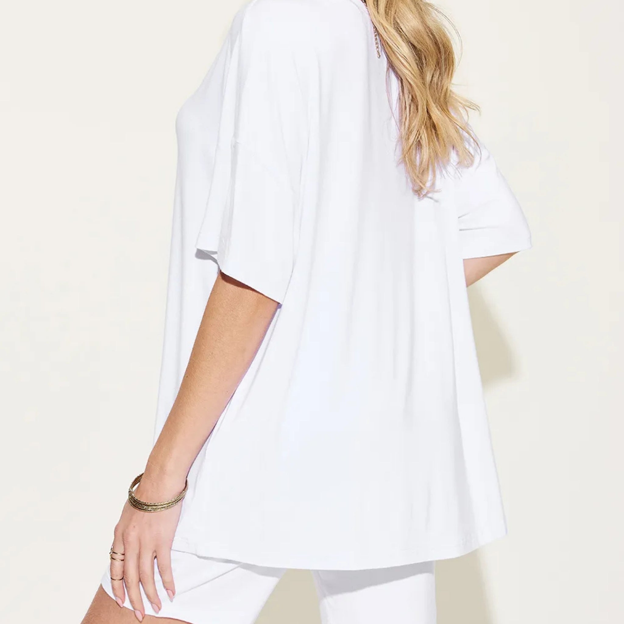 Person wearing a white oversized shirt on a plain background