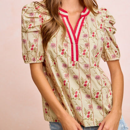 Woman wearing a floral blouse with a pink and white V-neckline on a pink background