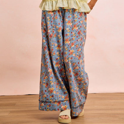 Floral patterned pants worn by a person on a wooden floor with a pink background