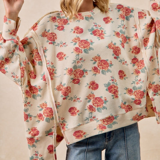 Floral patterned sweater worn by a person on a neutral background