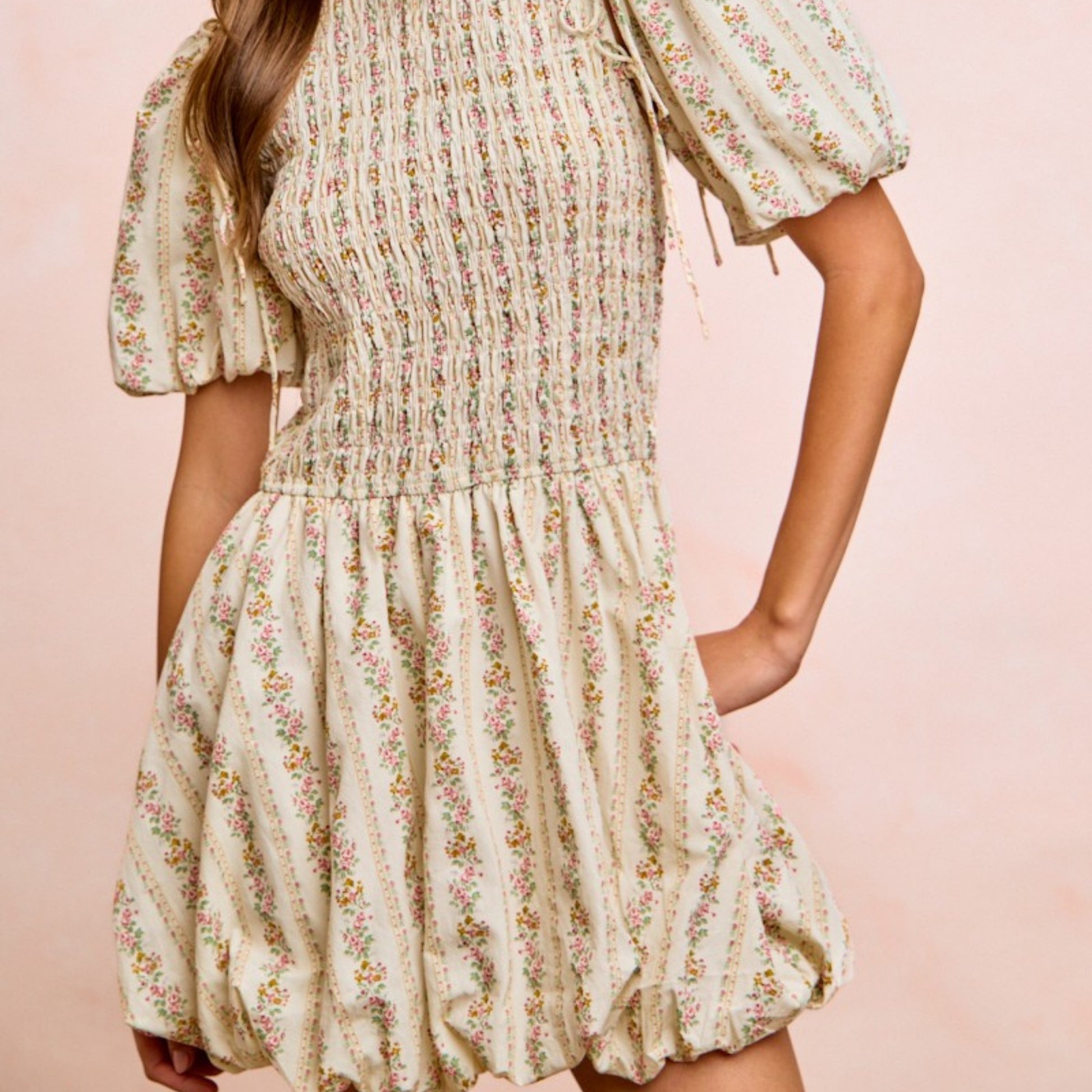 Floral dress worn by a person on a pink background