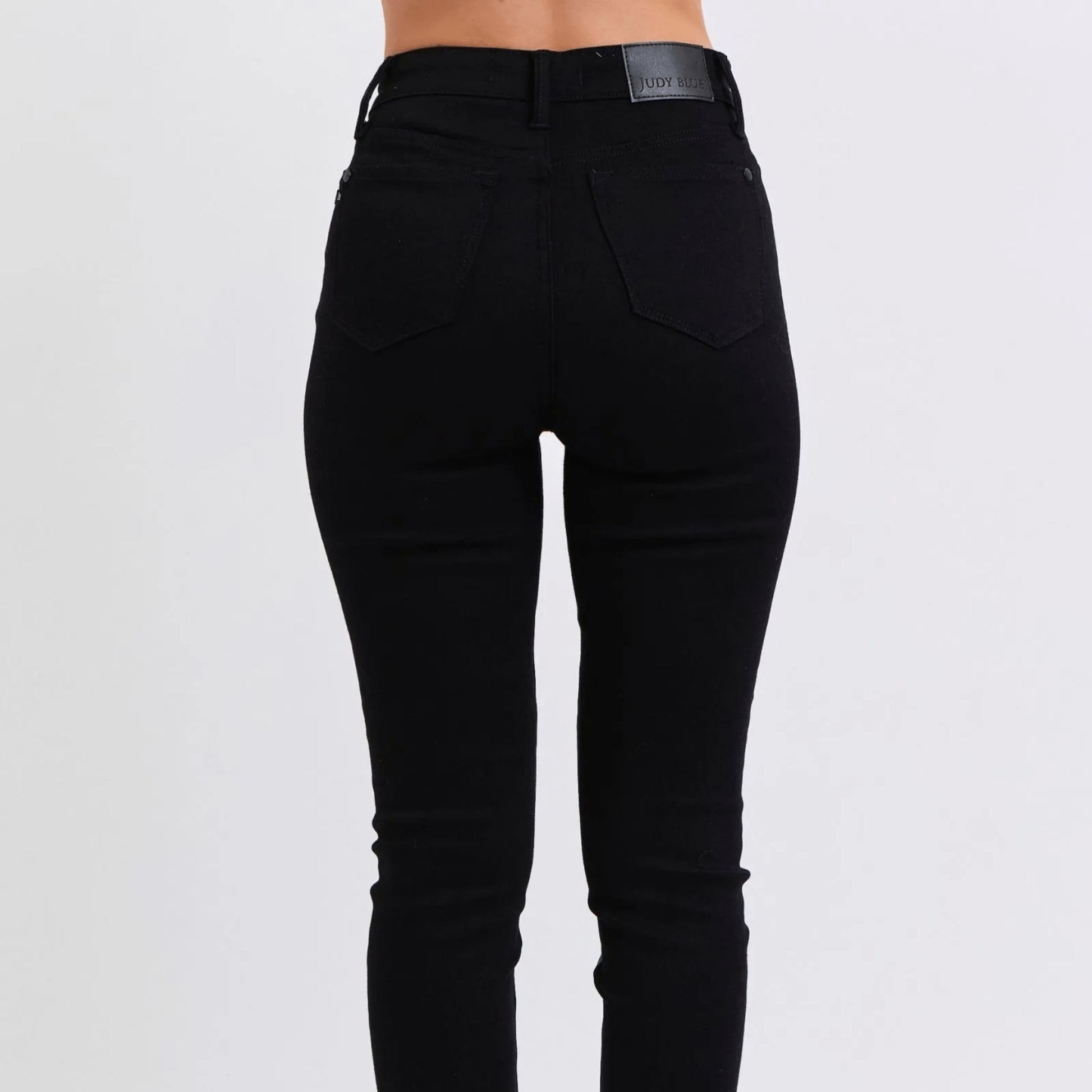 Lifestyle shot of black faux leather skinny pants styled for a fashion-forward look.