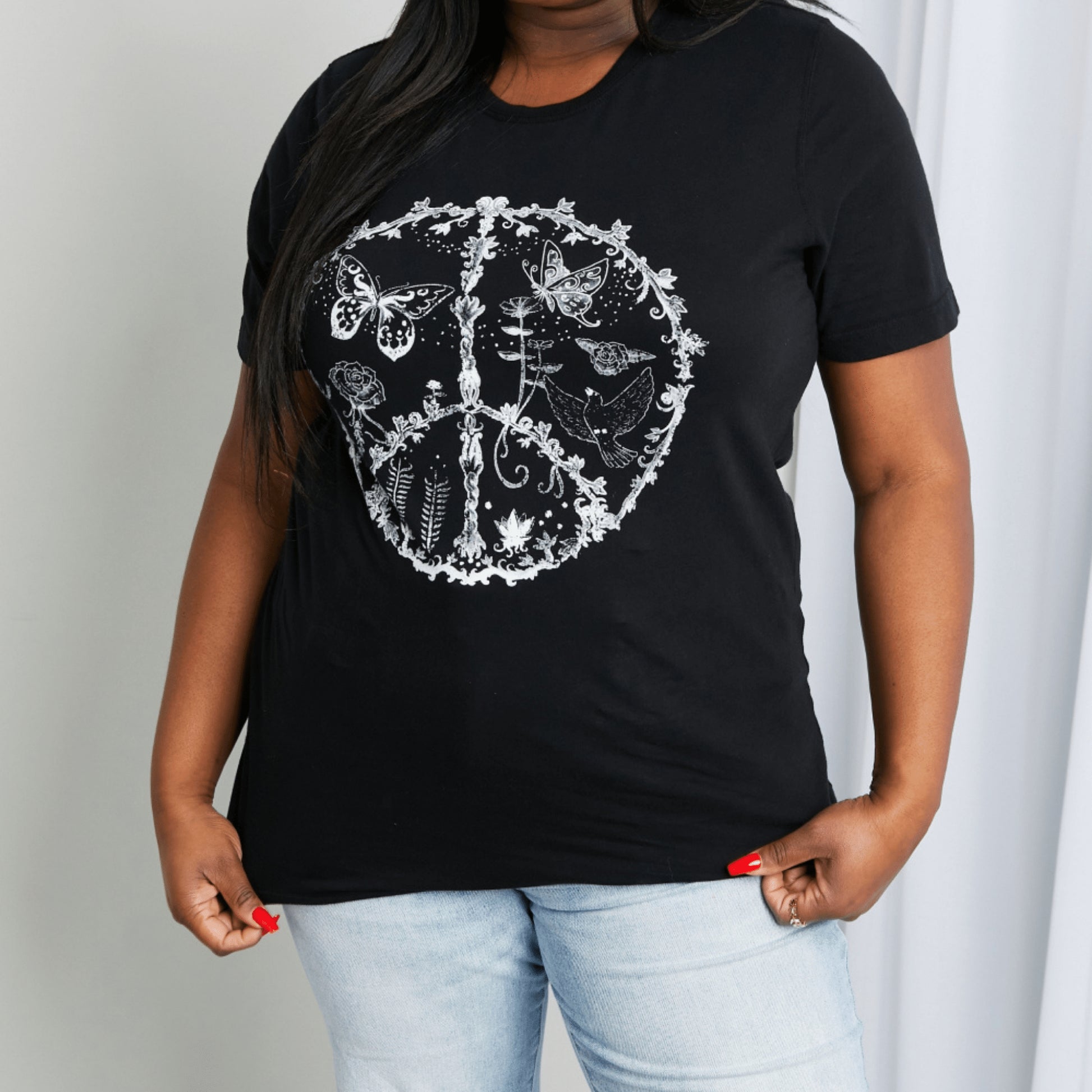 Frontal display of a woman wearing a black graphic T-shirt with a peace and butterfly print.