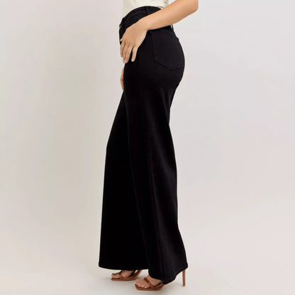 A woman wearing black wide-leg jeans and a white sleeveless top for a modern look.