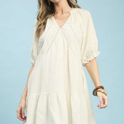 Woman wearing a light beige dress against a light blue background