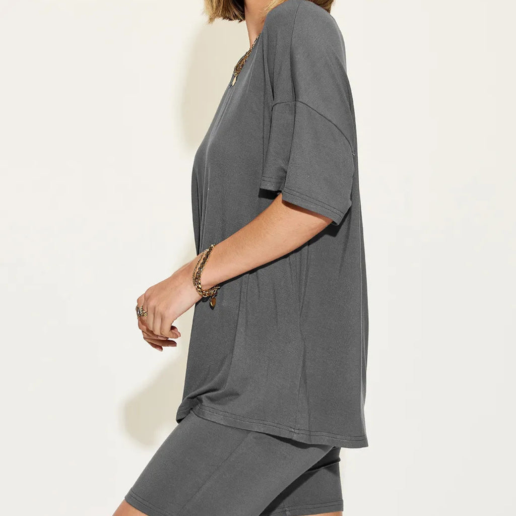 Person wearing a gray oversized t-shirt on a plain background