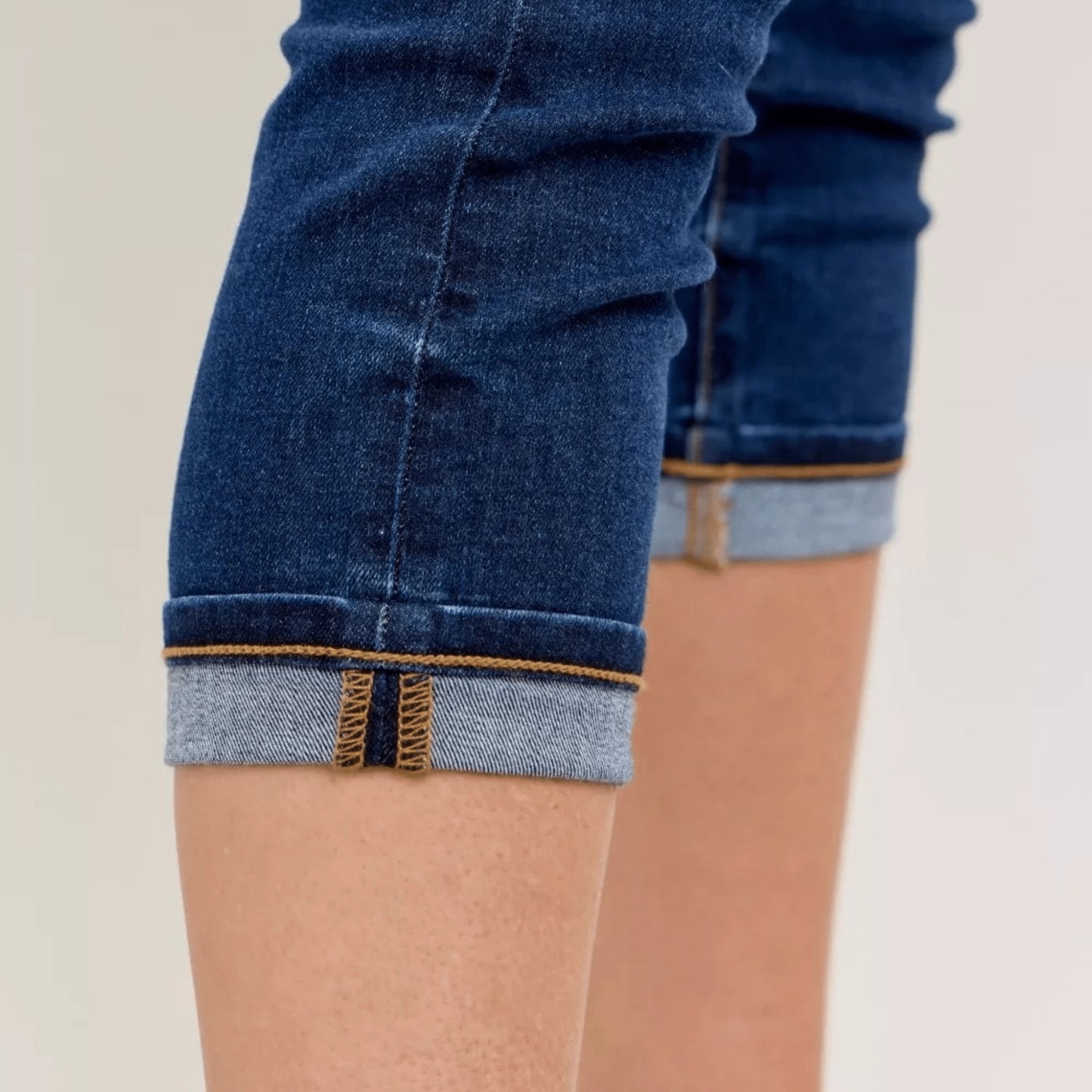 Detailed showcase of the fabric texture and cuff on dark wash capri jeans.