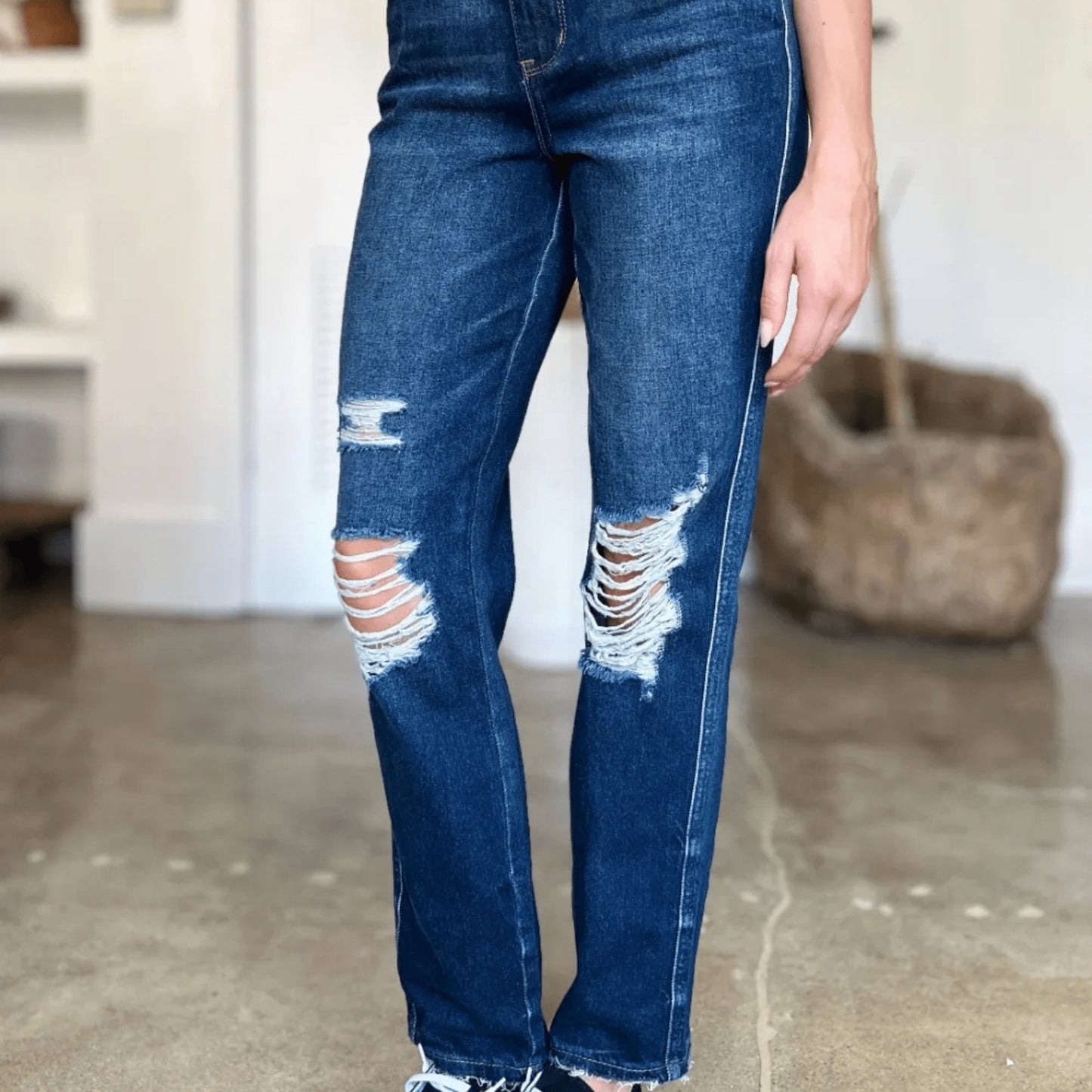 Model view of edgy dark wash jeans with heavy distressing details.
