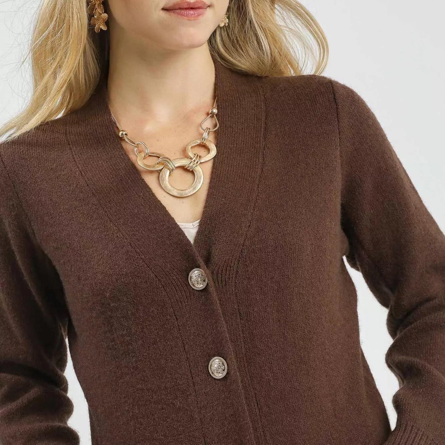 Close-up detail of the sophisticated gold-tone buttons on a brown knit longline cardigan for women.
