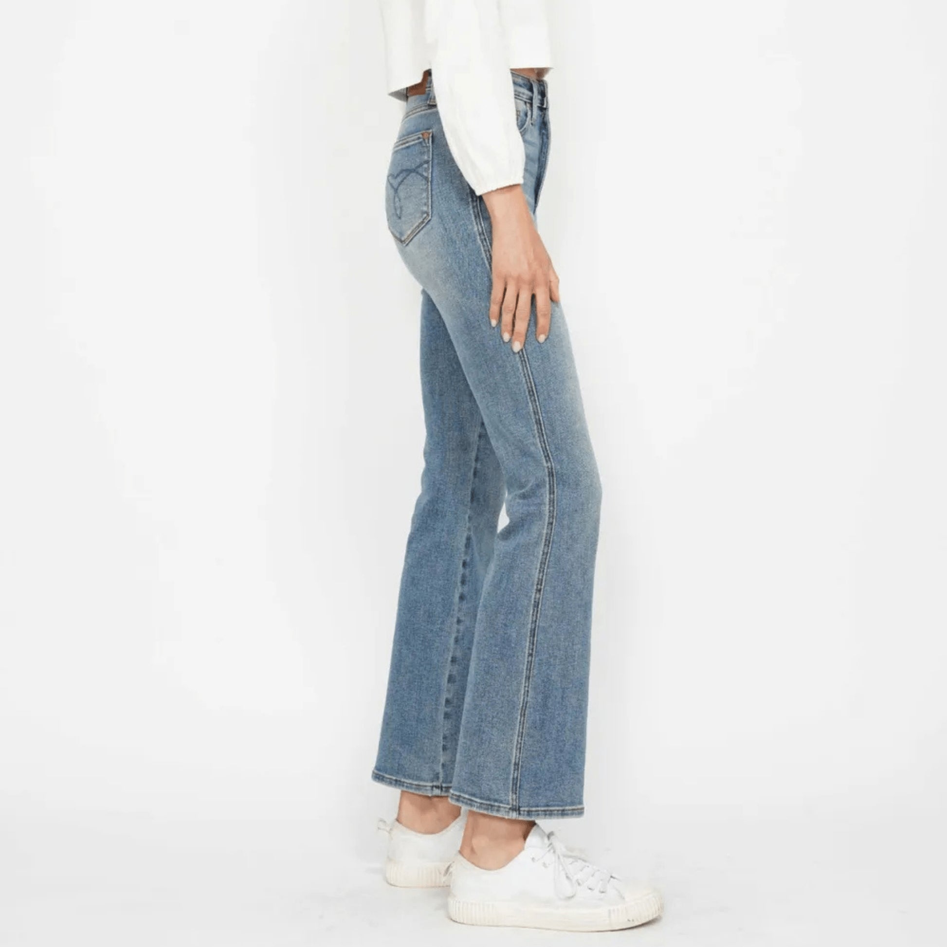 Side view of medium wash bootcut jeans highlighting the embroidered back pocket.