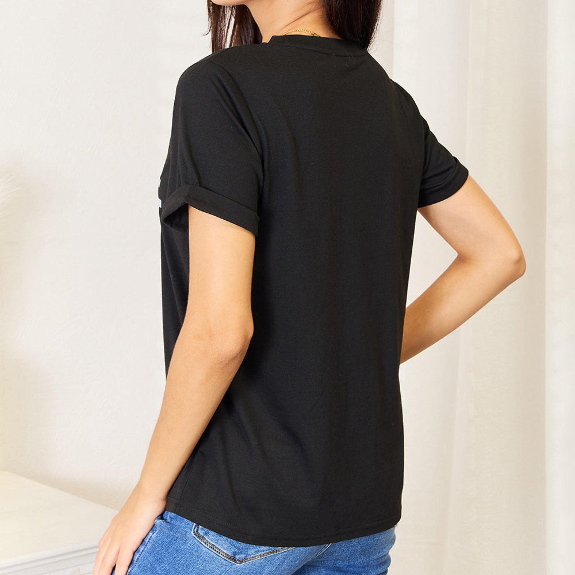 Back view of a black cuffed sleeve t-shirt showing the relaxed fit.