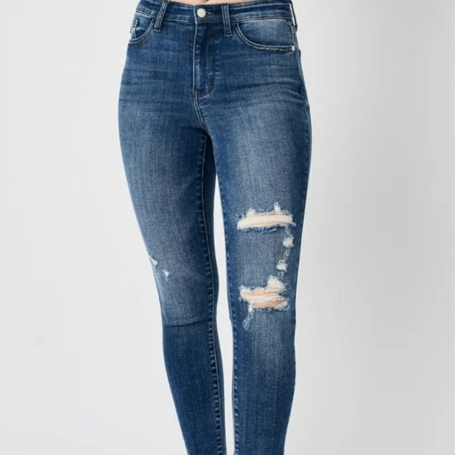 Front view of dark wash skinny jeans with distressed details.